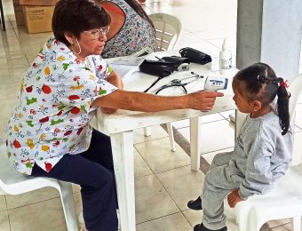 Enfermera del Hospital Padre Carollo toma de signos vitales a una niña de la comunidad Asunción